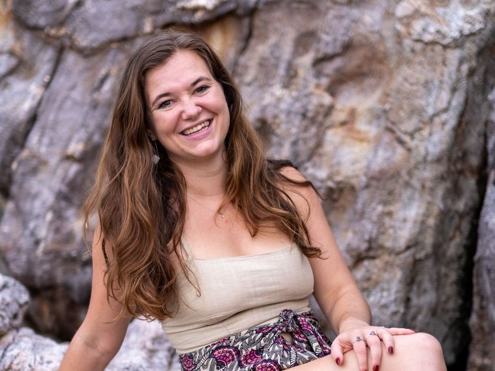 Mary Tichelaar laughing, sitting on rocks